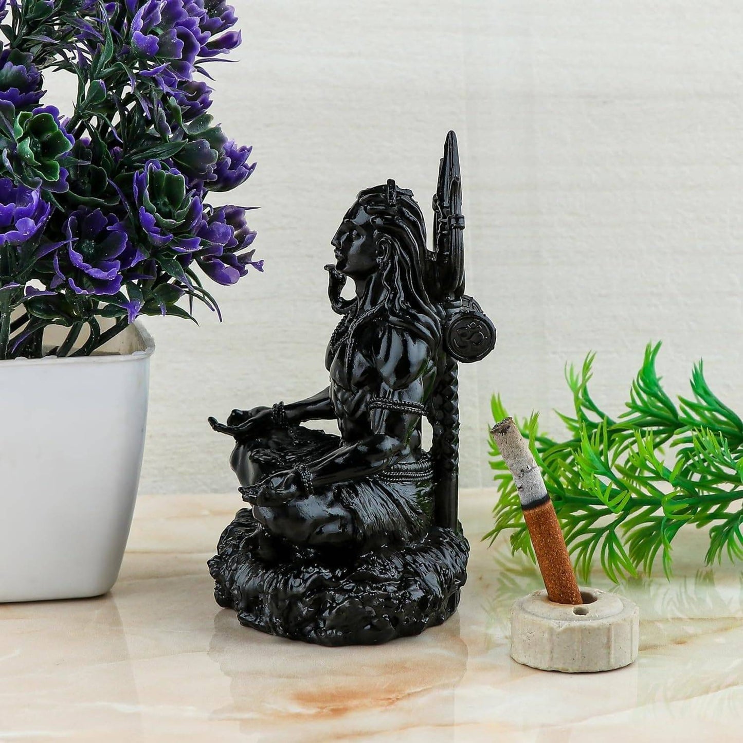 Adiyogi Meditation Statue placed on a table beside plants and incense holder, enhancing spiritual ambiance in home decor.